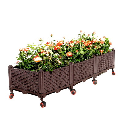 Individu arrosant le planteur en plastique entreposable augmenté rectangulaire de boîte de fleur de boîte de planteur